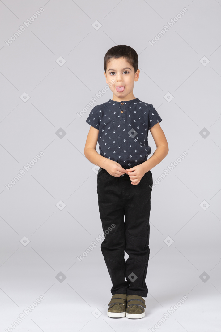 Front view of a cute kid boy looking at camera and showing tongue