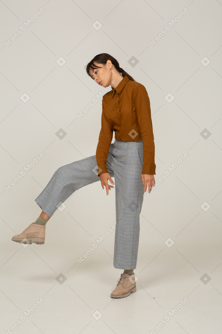 Front view of a young asian female in breeches and blouse raising leg