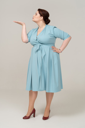 Вид спереди женщины в синем платье, отправляющей воздушный поцелуй