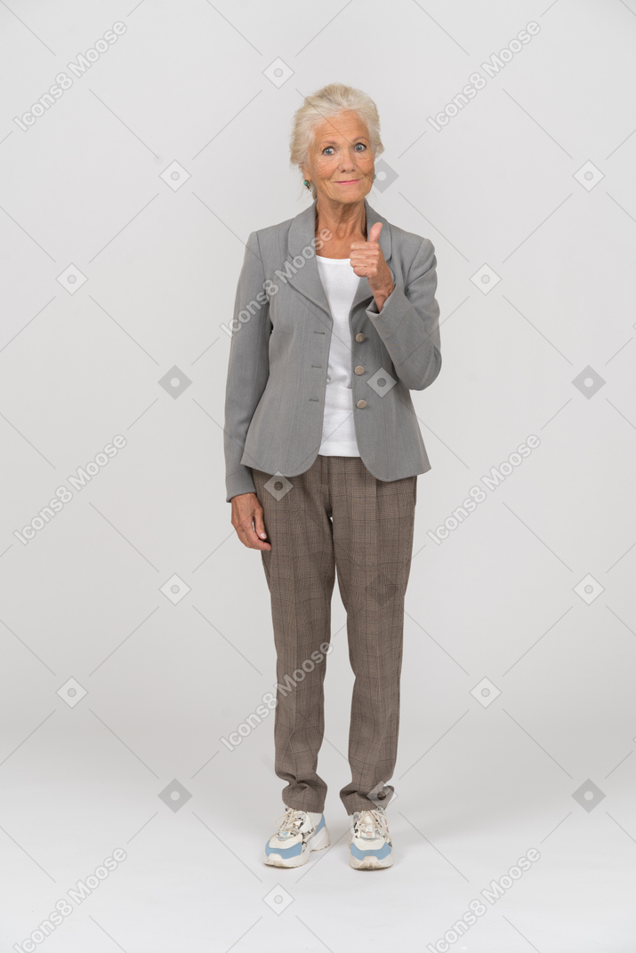Вид спереди счастливой старушки в костюме показывает палец вверх