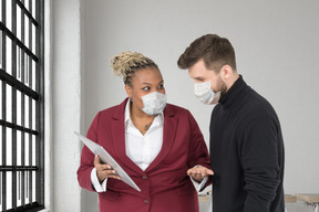 A woman with tablet and a man in face masks standing next to each other
