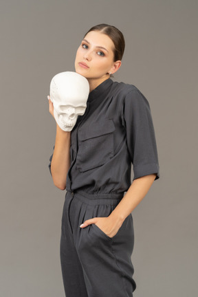 Вид спереди молодой женщины в комбинезоне с гипсовым черепом