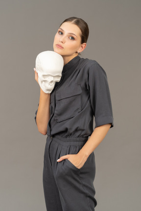 Front view of a young woman in a jumpsuit holding a plaster skull