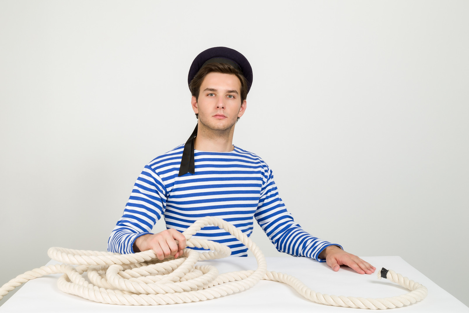 Proud sailor sitting at the table and holding rope