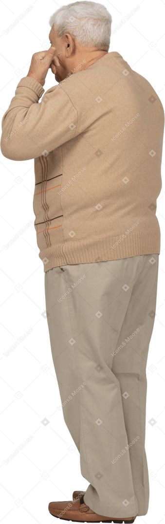 Vista lateral de un anciano con ropa informal poniendo los dedos en la boca