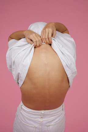 Young woman taking off her t-shirt