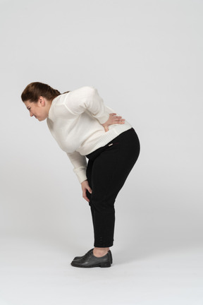 Mujer regordeta en ropa casual que sufren de dolor en la espalda baja