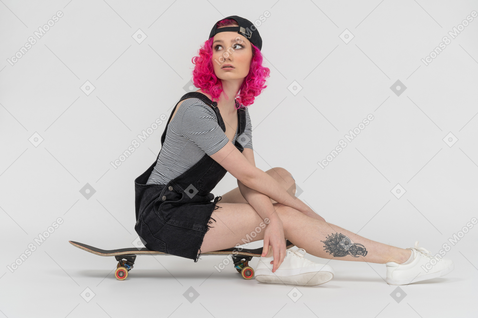A pink haired girl sitting on a skateboard