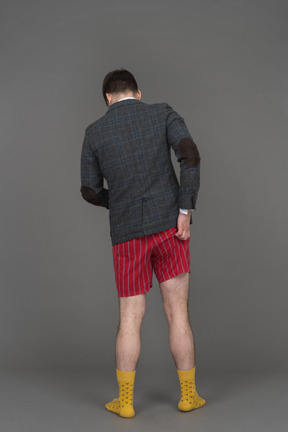 Man in red shorts and jacket scratching his butt back to camera