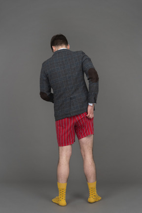 Homme en short rouge et veste se gratter les fesses à la caméra