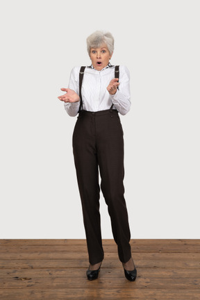 Vista frontal de una anciana sorprendida en ropa de oficina levantando sus manos