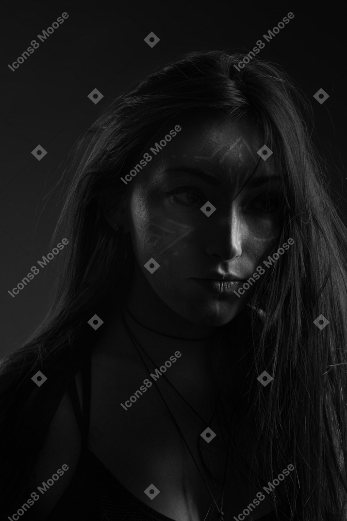 Крупным планом темный силуэт молодой женщины с фейс-артом смотрит в сторону