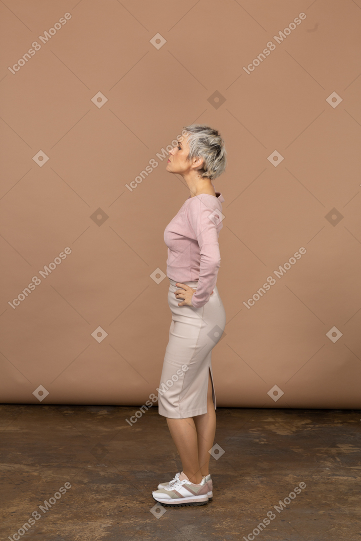 Woman in casual clothes standing in profile with hands in hips