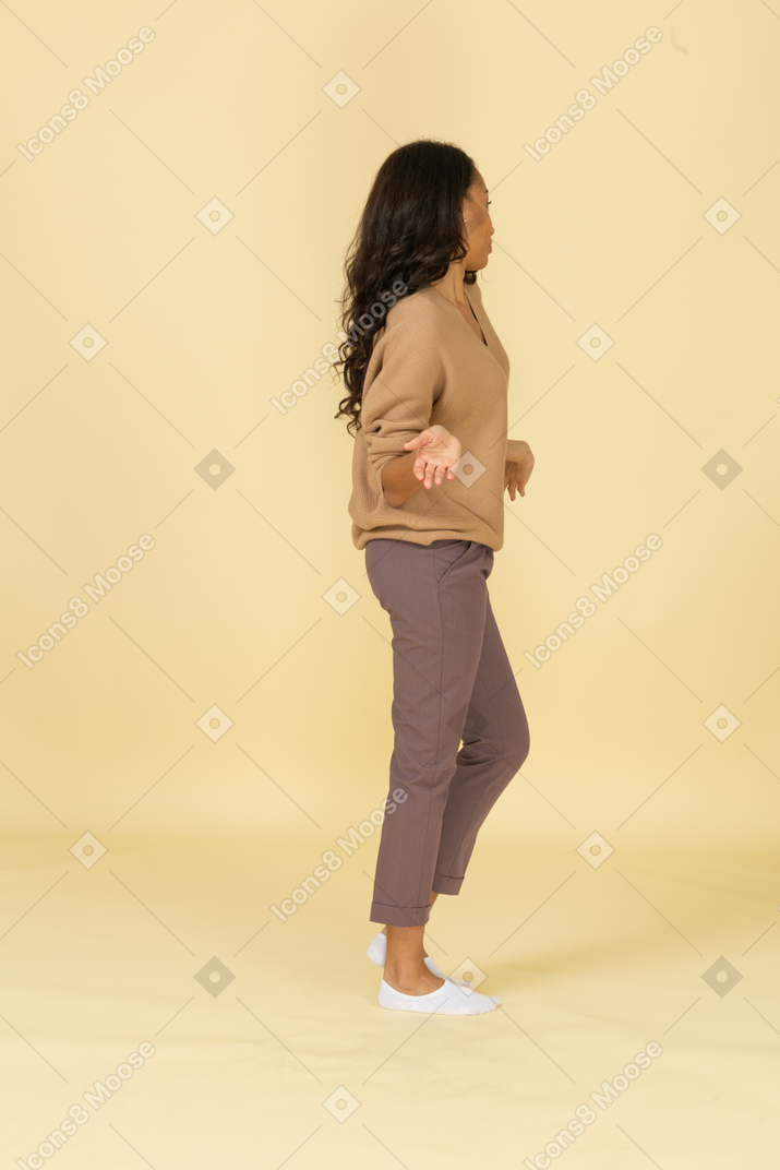 Side view of a dark-skinned careless young female outspreading her arms