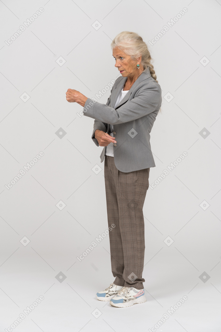 Vue latérale d'une vieille dame sérieuse en costume expliquant quelque chose