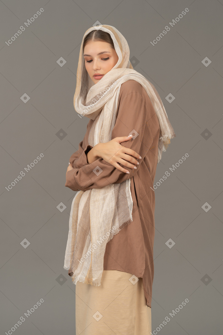 Mujer con ropa tradicional con las manos cruzadas mirando hacia abajo