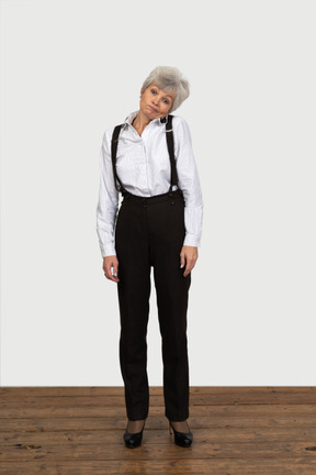 Front view of an old displeased female in office clothes feeling discomfort touching head to shoulder