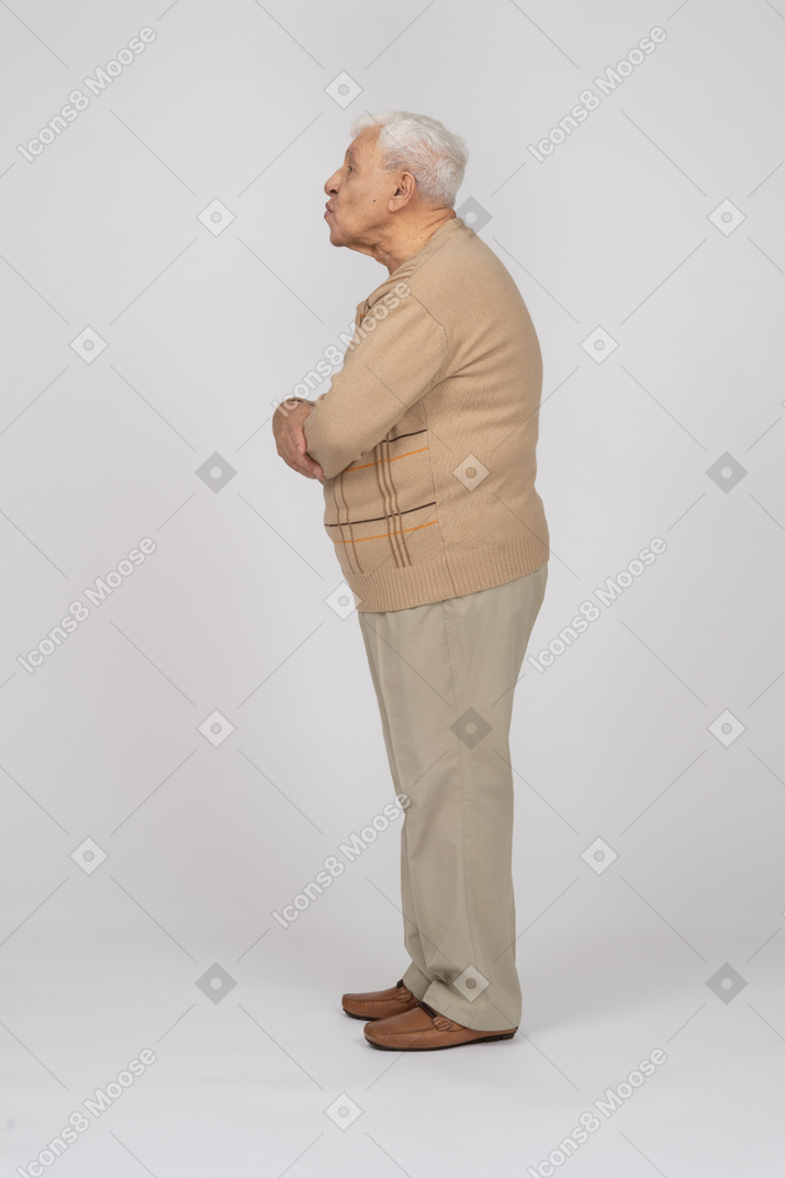Vista lateral de un anciano con ropa informal que sopla un beso