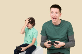 Excited man and his disappointed younger brother playing video games