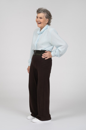 Vista di tre quarti di una donna anziana che sorride con una mano sull'anca