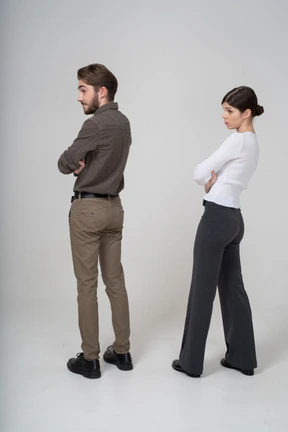 Three-quarter back view of a young couple in office clothing crossing arms