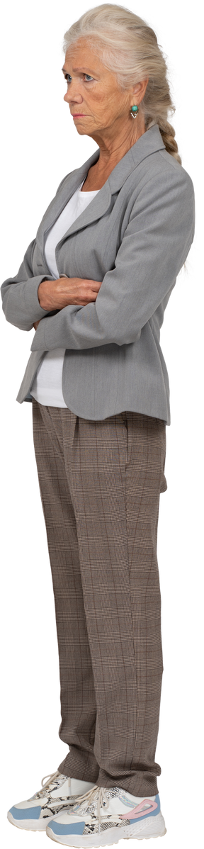 Vista lateral de una anciana en traje de pie con los brazos cruzados.
