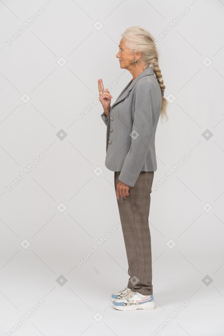 Seitenansicht einer alten dame im anzug, die mit den fingern ein v-zeichen macht