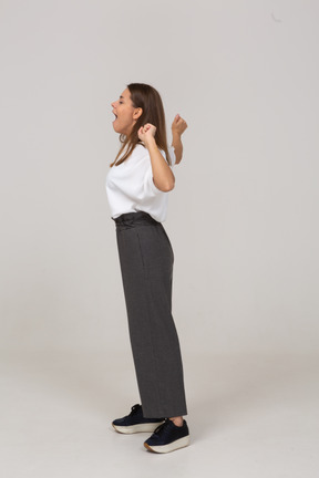 Side view of a yawning young lady in office clothing raising hands
