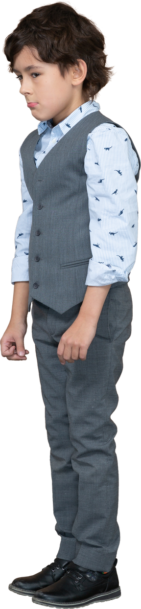 Vista lateral de un niño con traje gris parado