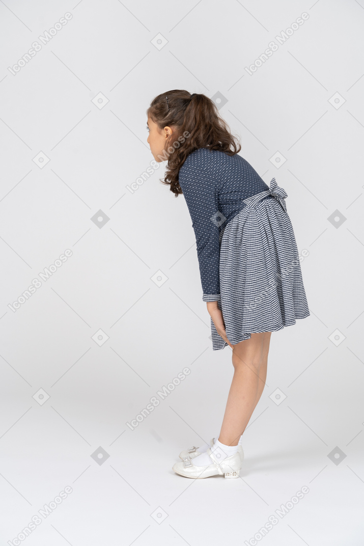 一个女孩身体前倾并伸手去拿膝盖的四分之三后视图