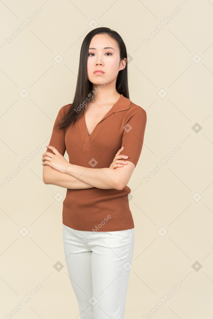 Sérieux cherche jeune femme asiatique debout avec les mains croisées