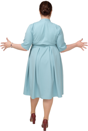 Женщина в синем платье жестикулирует, вид сзади
