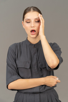 Front view of a young woman in a jumpsuit holding a pill on her tongue
