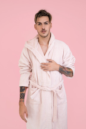 Attraktiver junger mann in rosa robe mit "ich verstehe nicht" gesichtsausdruck