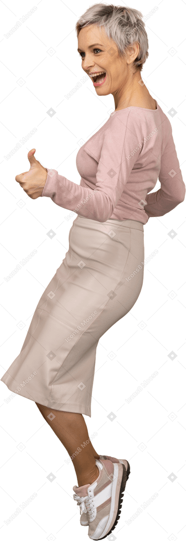 Вид сбоку женщины в повседневной одежде, стоящей на носках и показывающей большой палец вверх