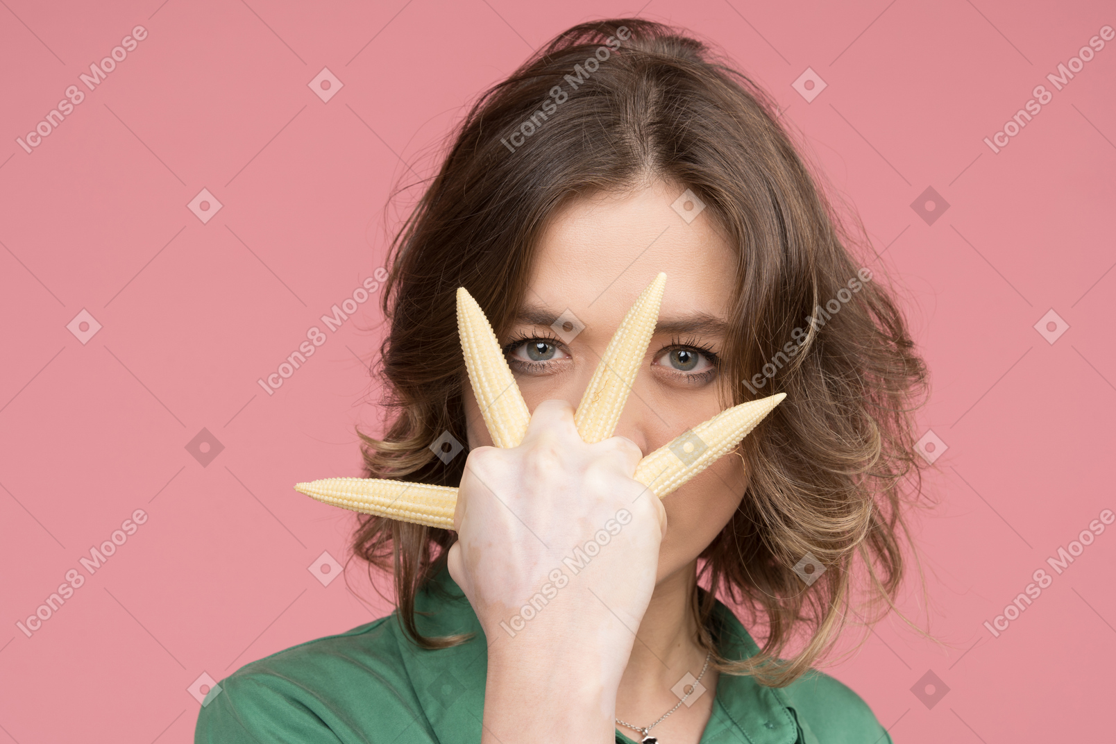 Confident woman holding baby corn in fist