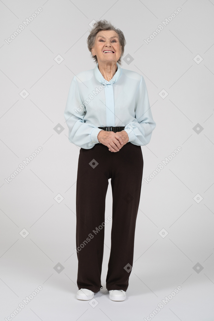 Vista frontal de una anciana con una sonrisa torcida y manos entrelazadas