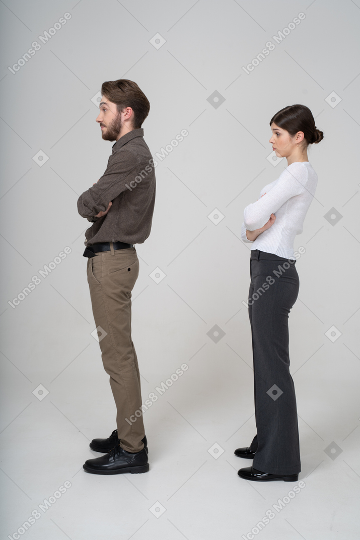 Side view of a young couple in office clothing crossing arms