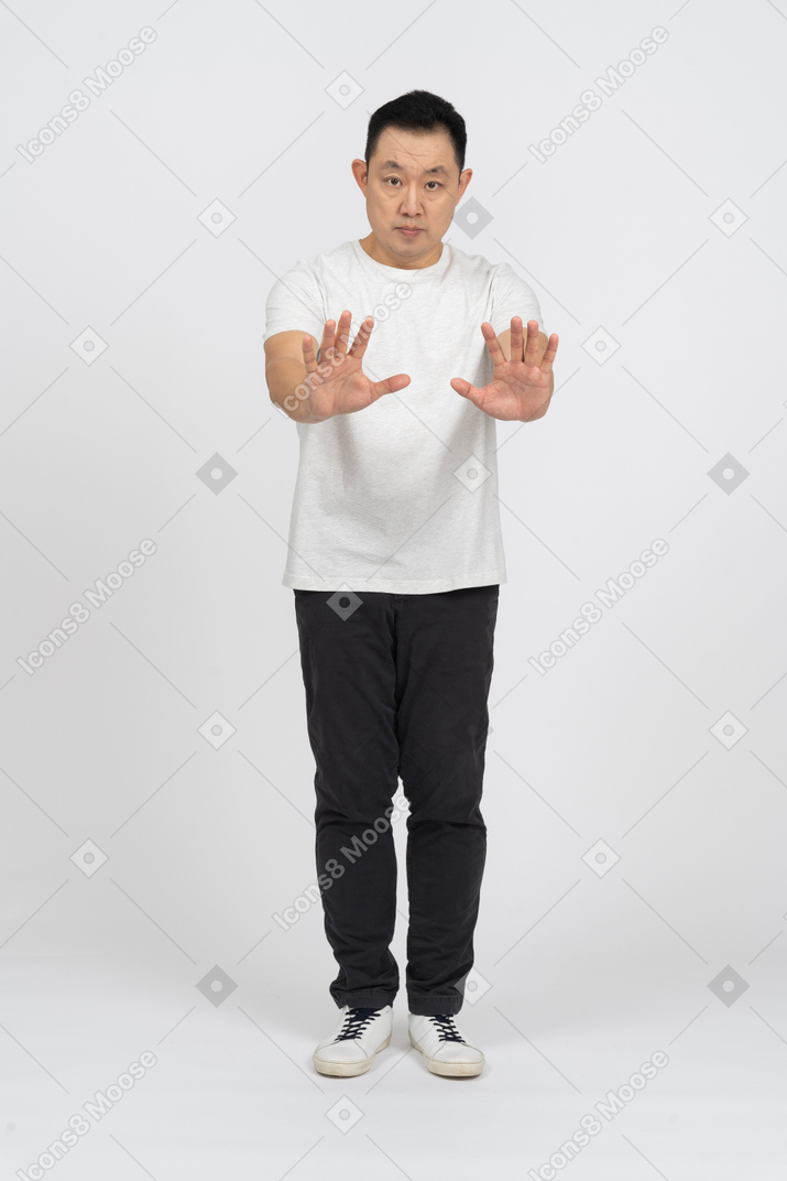Vue de face d'un homme en vêtements décontractés debout avec les bras étendus et regardant la caméra