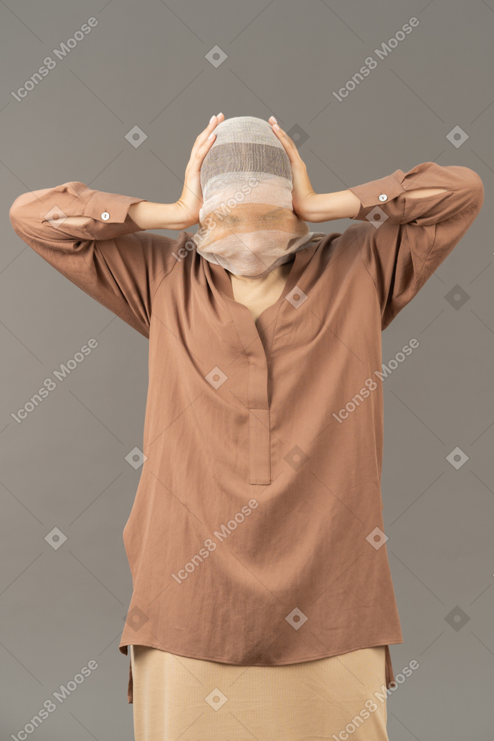 Woman covered with headscarf holding her head with both hands