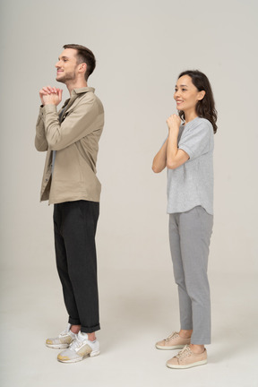 Side view of young couple portraying please gesture