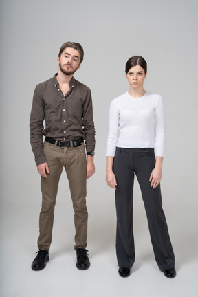一对年轻夫妇在办公室服装站着不动的前视图