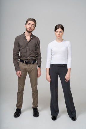 Front view of a young couple in office clothing standing still