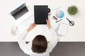 A female office worker at the table holding ipad