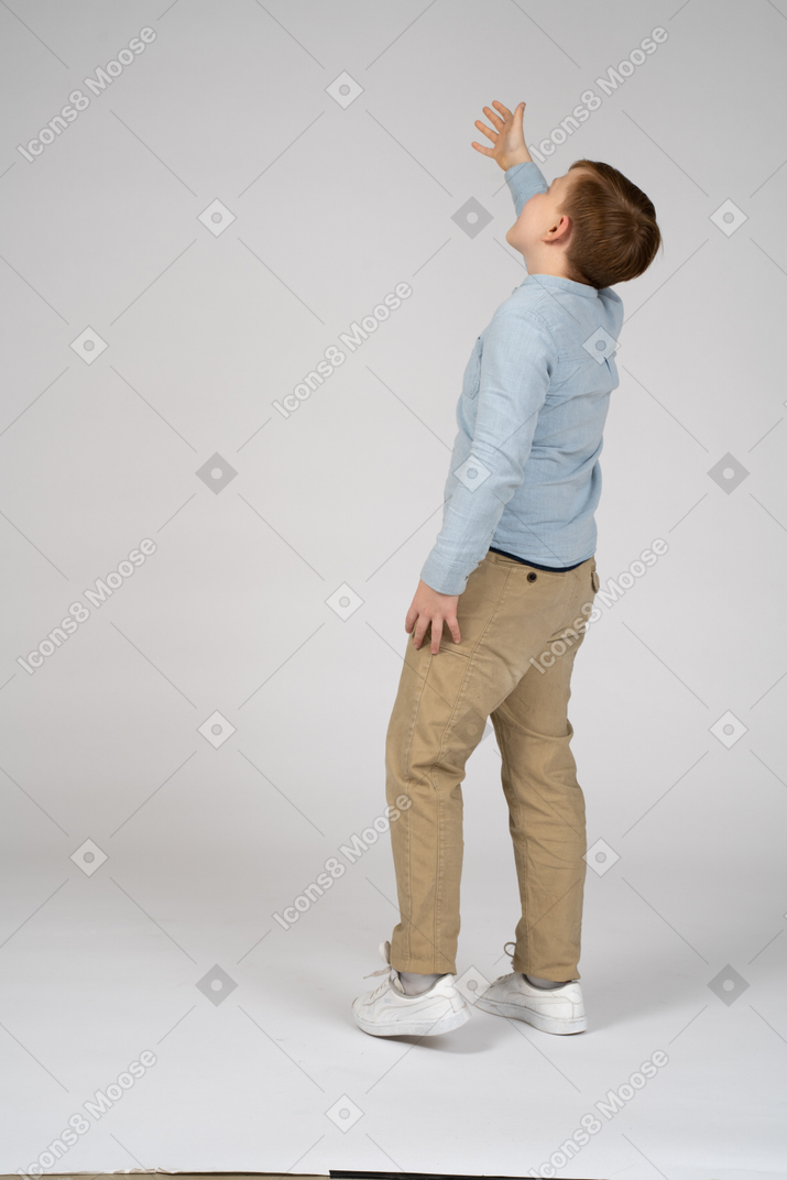 Side view of a boy looking up and waving