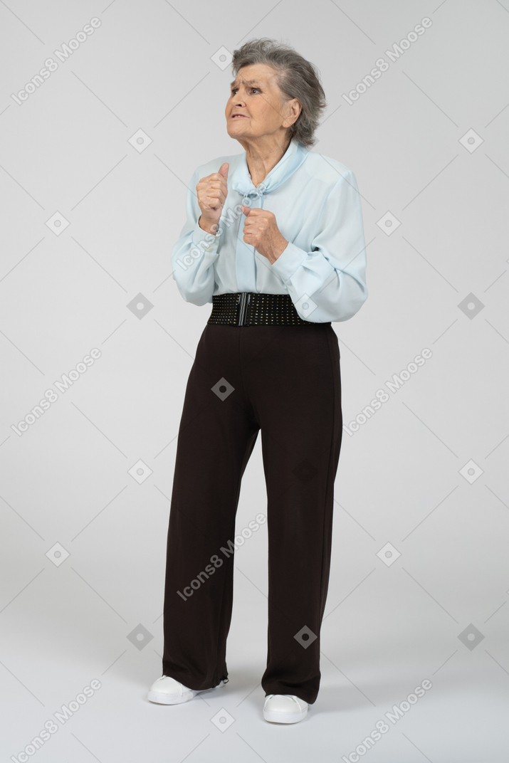 Вид спереди на пожилую женщину, тревожно сжимающую кулаки