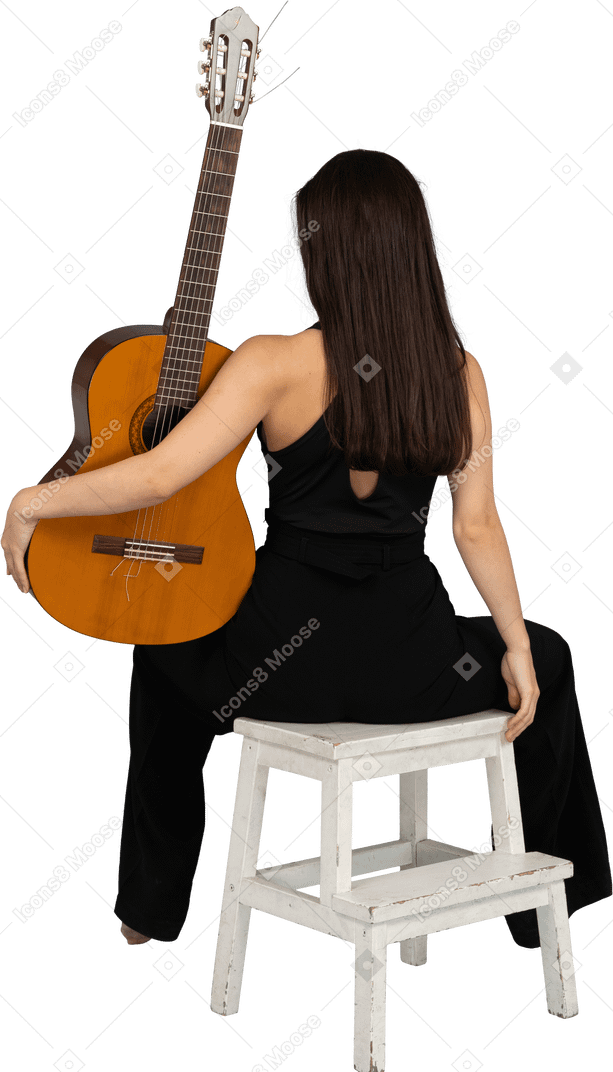 Vista traseira de uma jovem de terno preto segurando o violão e sentada no banquinho