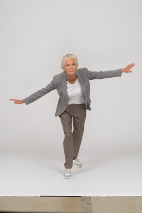 Front view of an old lady in suit standing with outspreading arms