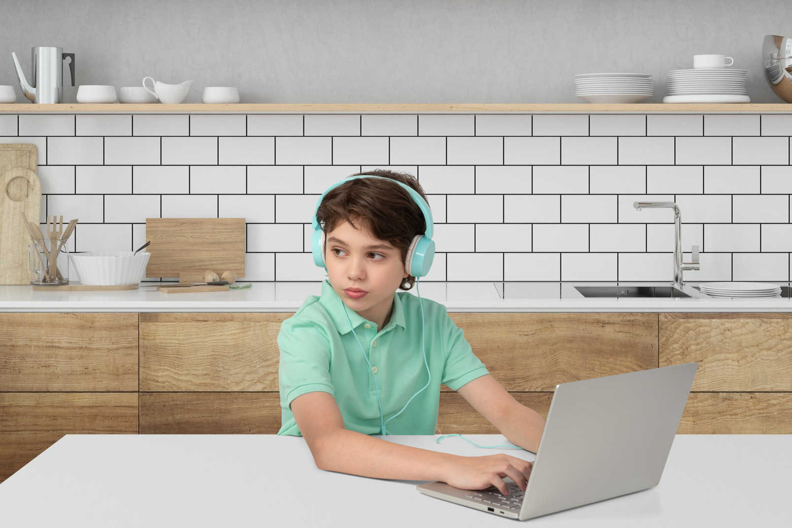 Young boy sitting at the table and working on laptop