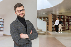 A man standing in a library with his arms crossed